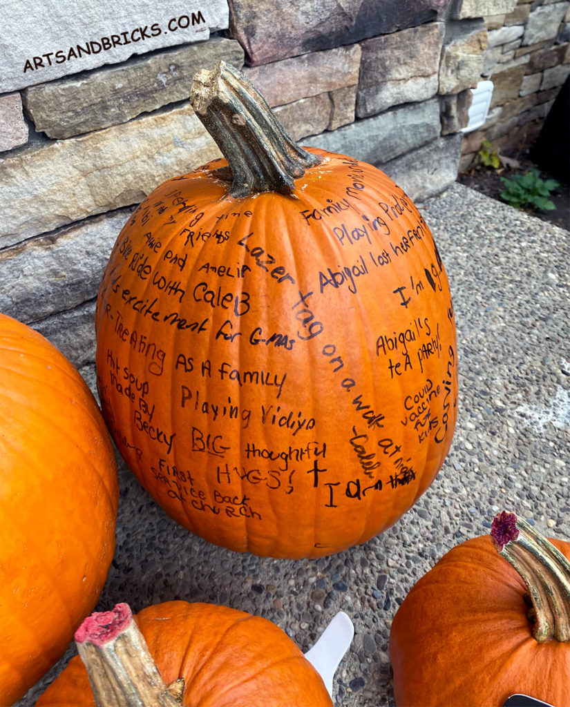 Example of family gratitude pumpkin. Joys and gratitudes are written with black sharpie marker on an orange pumpkin.